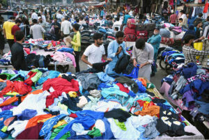 People selecting and purchasing secondhand clothes from vendors at Landa Bazaar.