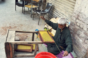 An old man is busy weaving a chair at his workplace near Lahore Hotel Road.