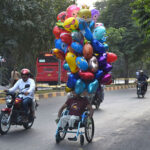 A disable person on the way for selling the colorful balloons while shuttling on the road on their wheel chair to earn for livelihood