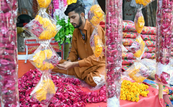A vendor arranging and displaying flower garlands to attract the customers at Banni Chowk