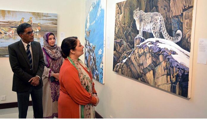 Coordinator to Prime Minister on Climate Change, Romina Khurshid Alam looking at a painting of snow leopard in its natural habitat displayed at the Wildlife Art Exhibition at PNCA in Federal Capital