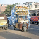 An auto rickshaw piled high with plastic bottles, showcasing resourceful transport in action
