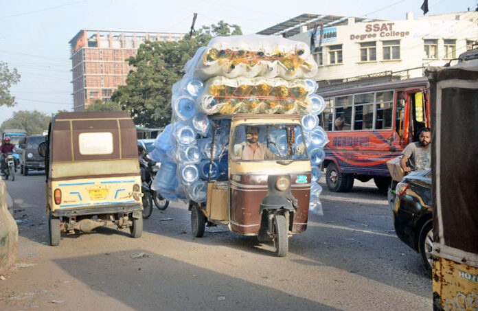 An auto rickshaw piled high with plastic bottles, showcasing resourceful transport in action