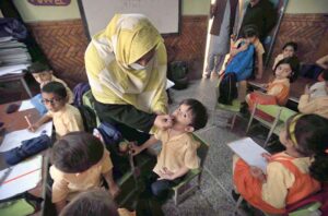 A female polio health worker administers polio drops to a child in a school during the anti-polio vaccination campaign aimed at eradicating polio in the provincial capital.