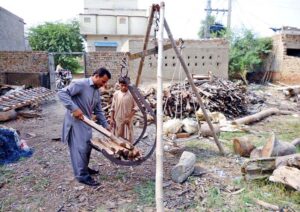 A man weighing pieces of timber wood for sale to customers at a timber store in the city.
