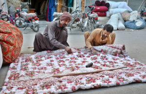 Workers diligently sewing traditional handmade quilts (polyester comforters) by hand. These affordable and lightweight quilts are in increasing demand as temperatures continue to drop in Quetta each passing day