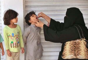A female polio health worker administers polio drops to a child in a school during the anti-polio vaccination campaign aimed at eradicating polio in the provincial capital.