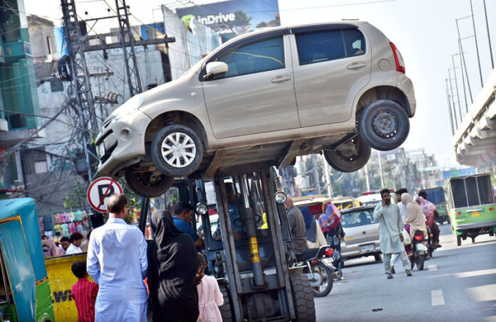 A traffic warden moving an illegally parked car with the help of lifter