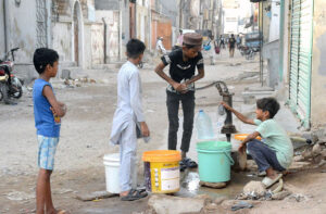 A boy pumps water with a hand pump to fill his pots for domestic use as the city faces a water shortage