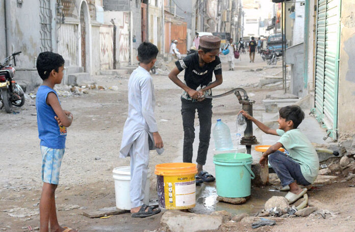 A boy pumps water with a hand pump to fill his pots for domestic use as the city faces a water shortage