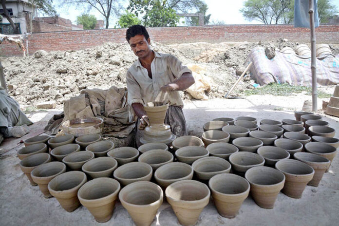 Craftsmen busy in preparing clay made pots at his workplace