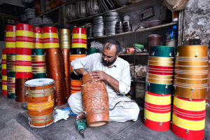 A shopkeeper prepares musical instrument drums (dholkas) at his shop for sale, as the wedding season ahead in the provincial capital.