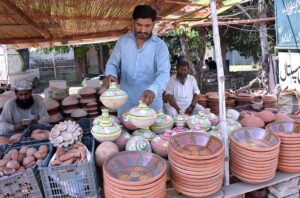A shopkeeper decorates pottery in his shop, striving to attract customers and earn a livelihood for his family.