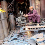 Labourer busy in cutting iron sheet with the help of gas cutter at his workplace