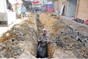 A laborer digs the ground to install drainage pipes in the Korangi area, contributing to essential infrastructure improvements in the provincial capital.