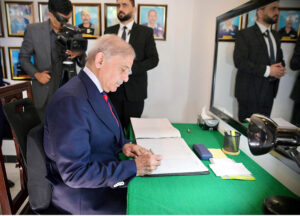 Prime Minister Muhammad Shehbaz Sharif writes his remarks in the visitors' book at the Police Lines Headquarters.