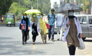 Women walk towards their destination under umbrellas to avoid the scorching sun near Shadman Road.