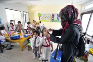 A female health worker administers polio drops to school children during a vaccination drive aimed at eradicating polio in Pakistan.