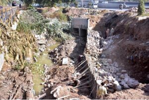 Labourers busy in construction work of bridge at service road along Karnal Sher Khan Shaheed Road during development work in the city.