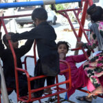 Children enjoy swings at roadside in the city