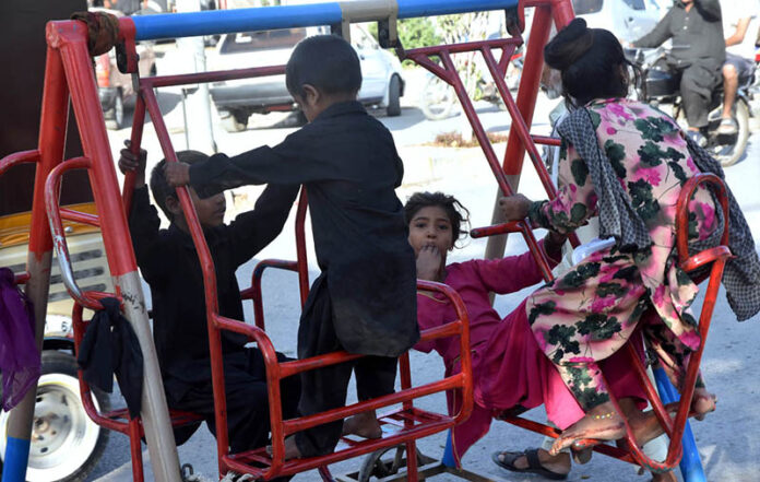 Children enjoy swings at roadside in the city