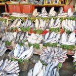 A vendor displaying fish to attract customers at his setup in a local market