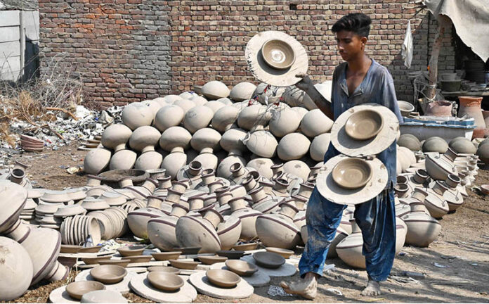 A worker arranging clay-made stuff for drying purpose at his workplace in Kumharpara at Jamshoro Road