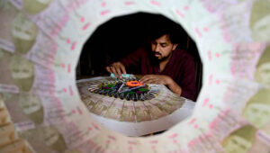 Wedding 'bills': A craftsman clips together crisp banknotes to form a traditional wedding garland for grooms.