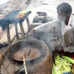 A vendor busy roasting corn cobs for customer at his roadside setup in Federal Capital