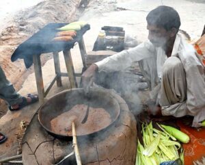 A vendor busy roasting corn cobs for customer at his roadside setup in Federal Capital