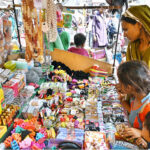 A woman selecting and purchasing different items displayed by vendor at Tower Market
