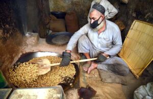 A vendor roasting peanuts at his workplace.