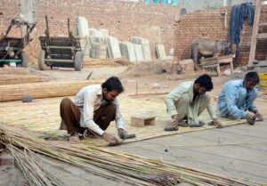 'Behind the curtains': Workers bind bamboo sticks side by side to craft a traditional blind called 'Chik', to be further sewn with a layer of cloth.