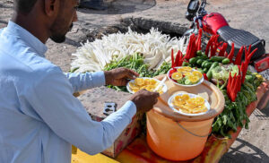 A street vendor prepares glasses of fresh pomegranate juice to attract customers at his stall in Pirwadhai, twin cities.