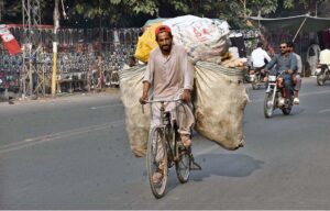A nomad pedals away on his bicycle, carrying valuables collected from a garbage heap to sell and provide for his family's livelihood .