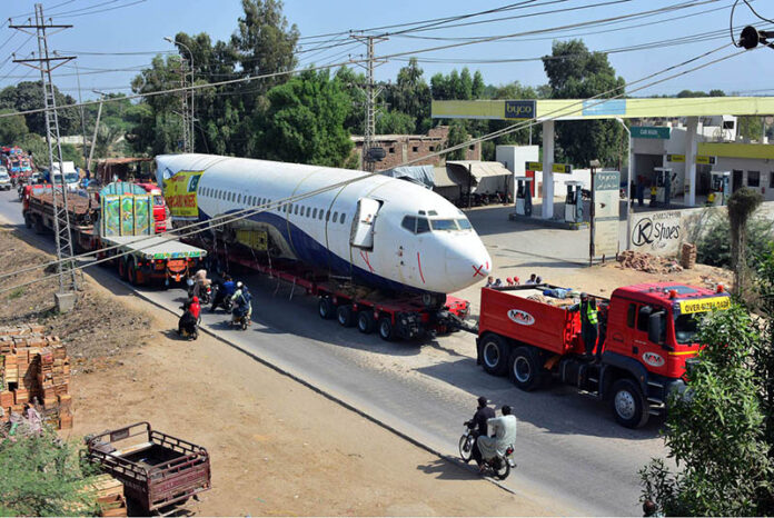 A heavy trailer transports a retired Boeing 737 airplane from Karachi to Hyderabad Airport