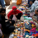 Vendor displaying ladies embroidery laces to attract the customer at cloth market road