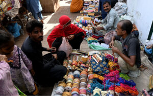 Vendor displaying ladies embroidery laces to attract the customer at cloth market road