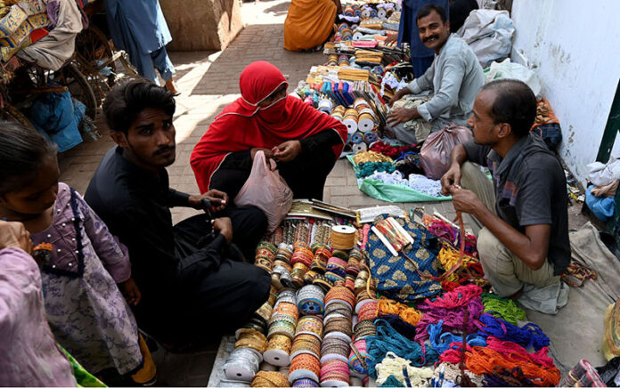 Vendor displaying ladies embroidery laces to attract the customer at cloth market road