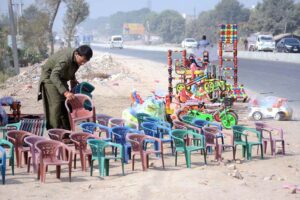 A vendor displaying chairs for children and different items to attract customers at Syed Wala Chowk