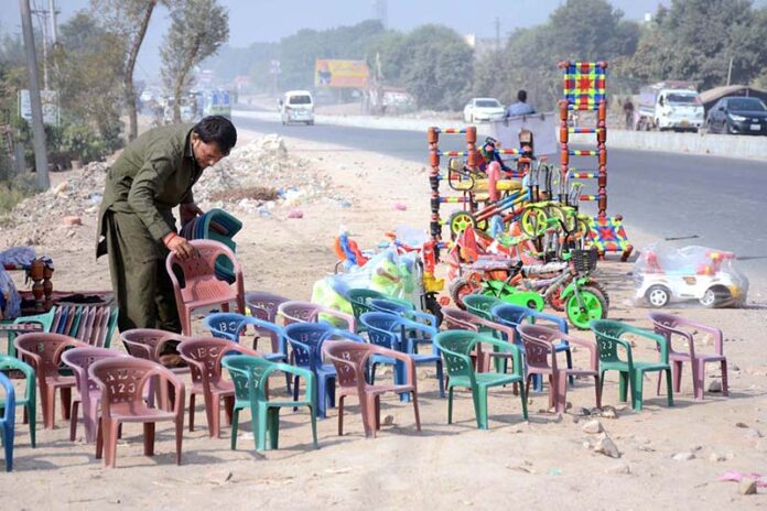 A vendor displaying chairs for children and different items to attract customers at Syed Wala Chowk