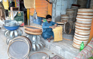 A worker is busy making iron sieves at his workplace.