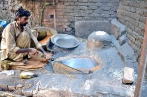 A worker busy roasting grams for customers at his workplace.
