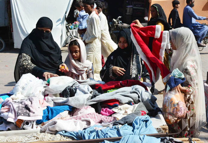 Women busy in selecting and purchasing old warm cloth from vendor during winter season
