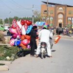 Street vendor selling colorful balloons to attract customers while shuttling on road in the Federal Capital