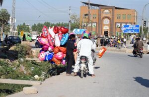 Street vendor selling colorful balloons to attract customers while shuttling on road in the Federal Capital