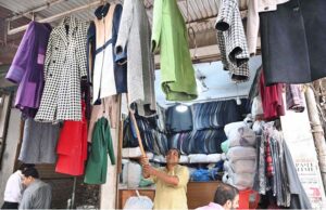A vendor is arranging and displaying warm coats at Anarkali Bazaar to attract customers
