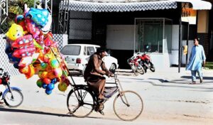 Street vendor selling colorful balloons to attract customers while shuttling on road in the Federal Capital