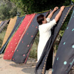 Vendor displaying colorful traditional Embroidery Chadar (Shawls) to attract customers at roadside setup