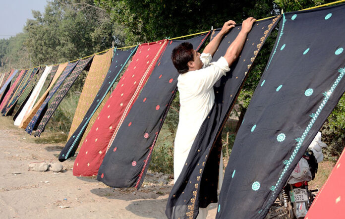 Vendor displaying colorful traditional Embroidery Chadar (Shawls) to attract customers at roadside setup
